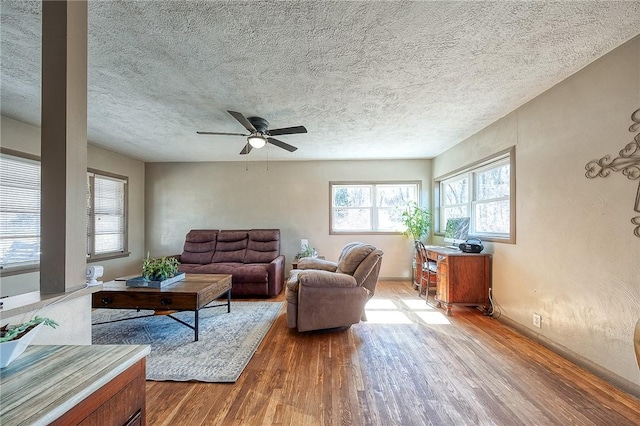 living area with a textured ceiling, ceiling fan, and wood finished floors