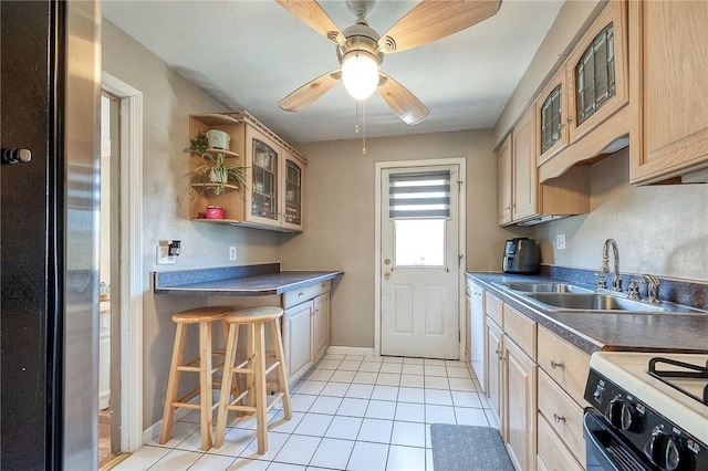 kitchen with glass insert cabinets, gas range oven, freestanding refrigerator, and a sink