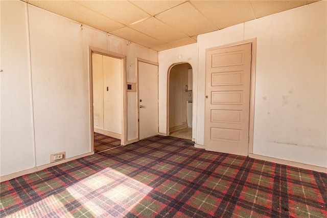 spare room featuring arched walkways, carpet flooring, and a paneled ceiling