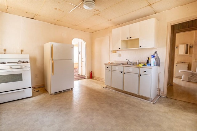 kitchen featuring white cabinetry, white appliances, arched walkways, and a drop ceiling