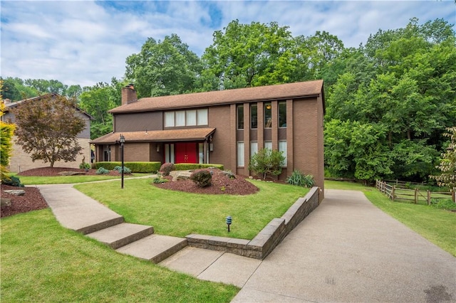 view of front of property with brick siding, a chimney, a front lawn, and fence