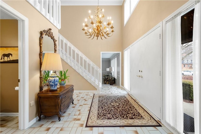 entryway with stairway, baseboards, a high ceiling, crown molding, and a chandelier