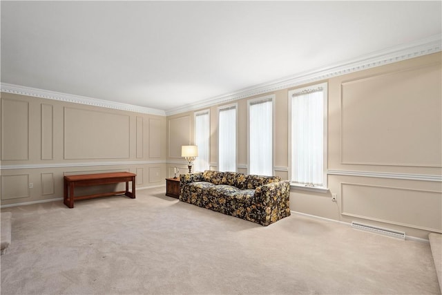 sitting room featuring visible vents, light carpet, crown molding, and a decorative wall