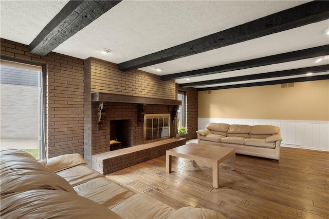 living room with hardwood / wood-style floors, a fireplace, wainscoting, and a textured ceiling