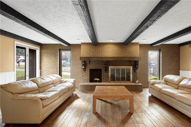 living area featuring a healthy amount of sunlight, a fireplace, light wood-type flooring, and a textured ceiling