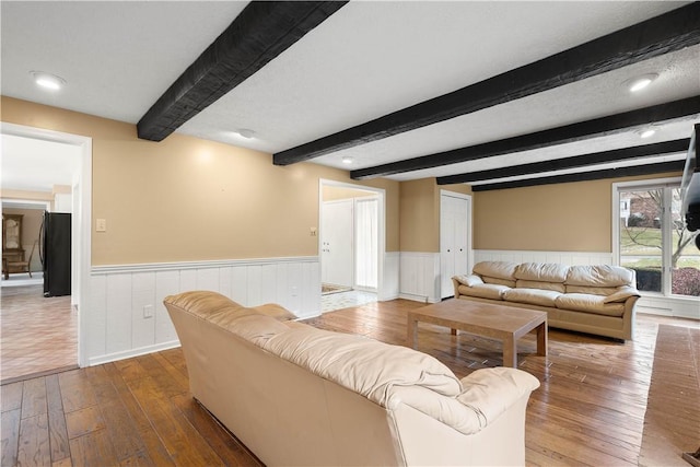 living room featuring beamed ceiling, wainscoting, and wood-type flooring