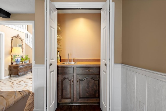 bar with a sink and a wainscoted wall