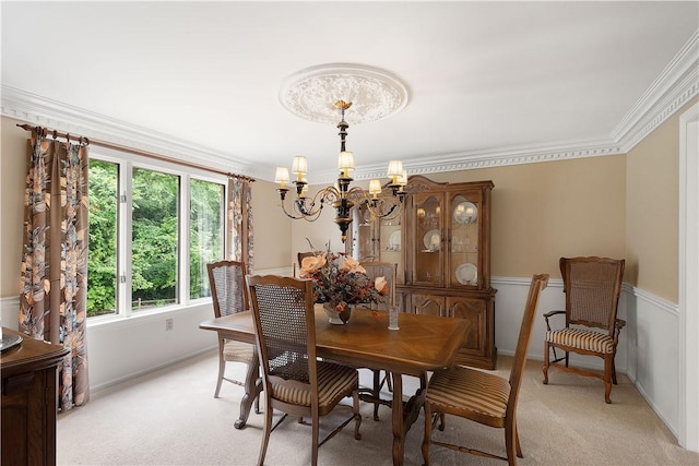 dining space with an inviting chandelier, ornamental molding, and light carpet