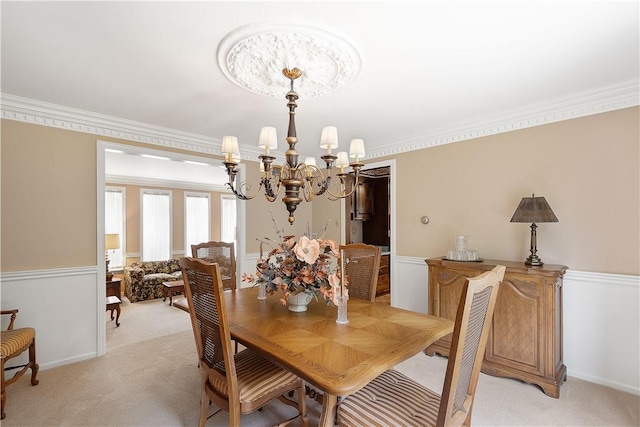 dining area with light carpet, an inviting chandelier, and ornamental molding