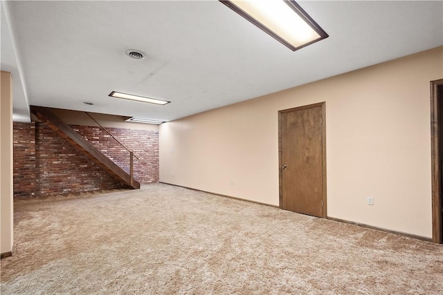 finished below grade area with stairway, carpet floors, visible vents, and brick wall