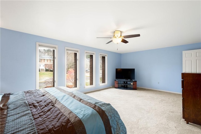 carpeted bedroom with multiple windows, a ceiling fan, and baseboards