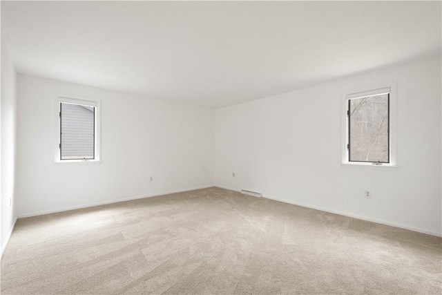 empty room featuring baseboards, visible vents, and light carpet