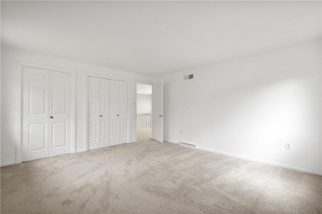 unfurnished bedroom with baseboards, visible vents, two closets, and carpet floors