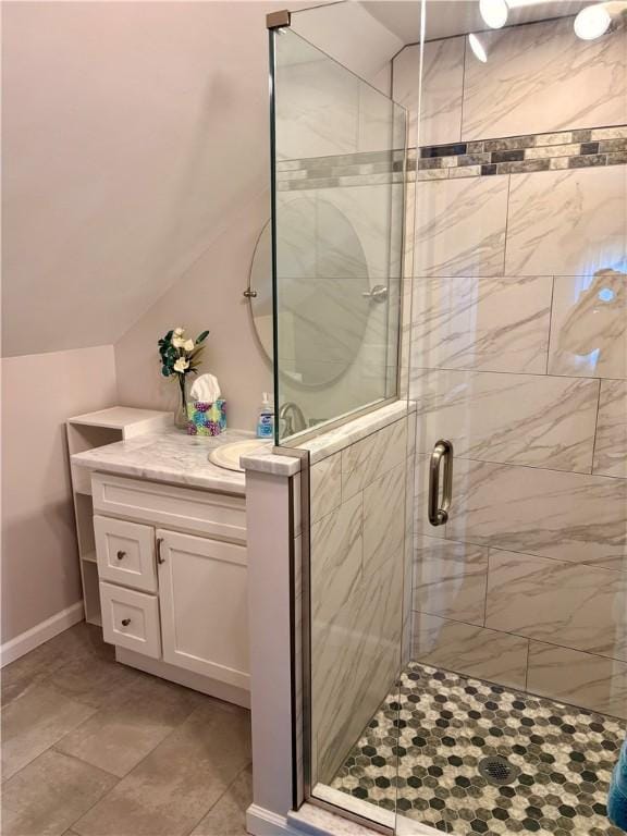 full bathroom featuring a shower stall, vanity, baseboards, and vaulted ceiling