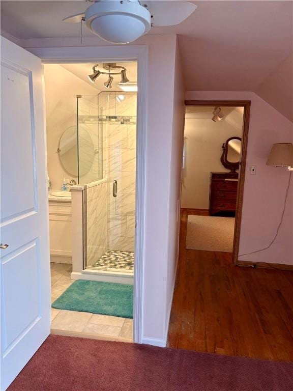 bathroom featuring a shower stall, wood finished floors, a ceiling fan, and vaulted ceiling