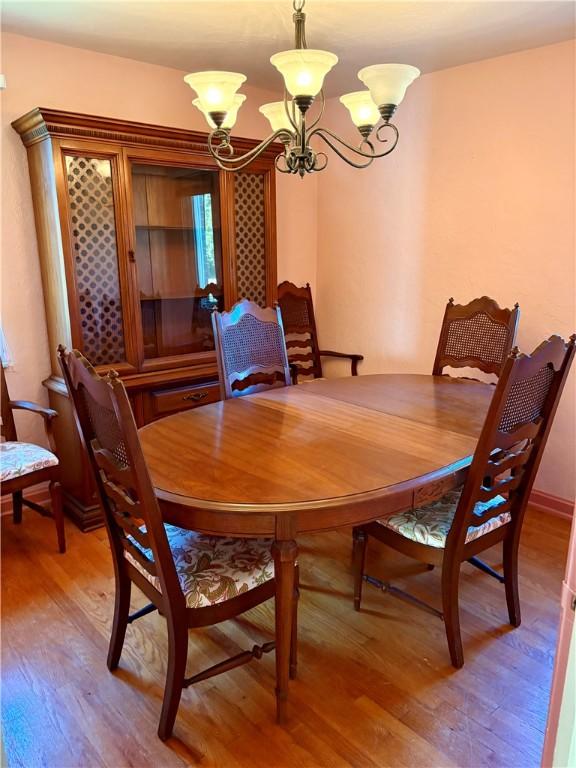 dining space featuring a notable chandelier, baseboards, and light wood finished floors