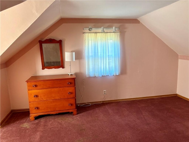 additional living space featuring baseboards, lofted ceiling, and dark carpet