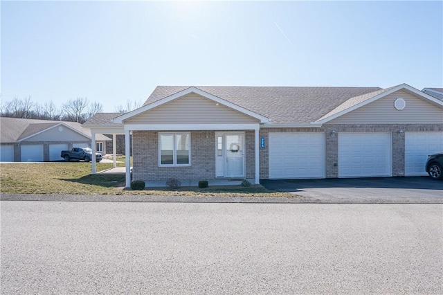 ranch-style house featuring roof with shingles, an attached garage, a front lawn, aphalt driveway, and brick siding