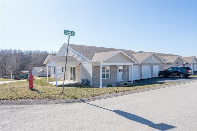 view of front of home featuring a front yard, roof with shingles, an attached garage, aphalt driveway, and brick siding