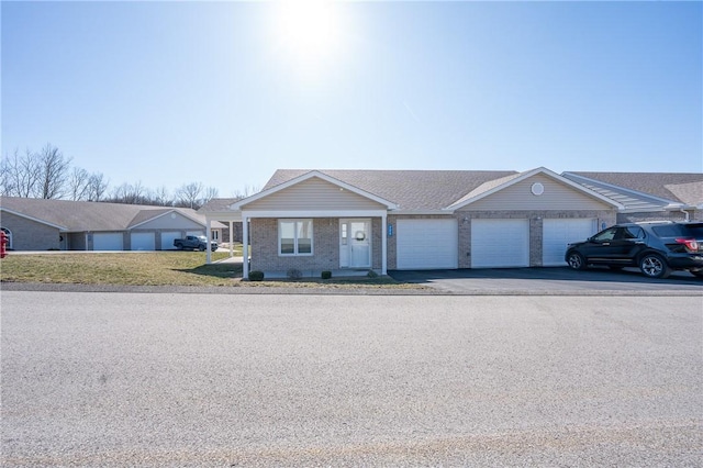 ranch-style house featuring aphalt driveway, an attached garage, brick siding, and roof with shingles