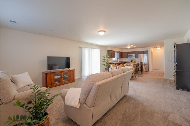 living area featuring visible vents, baseboards, and light colored carpet