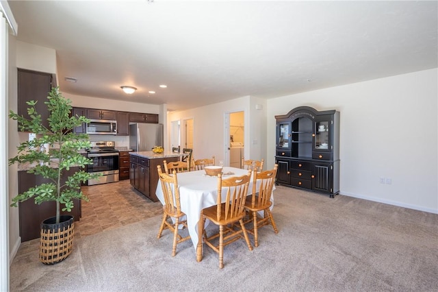 dining space with baseboards, light colored carpet, and washer / dryer