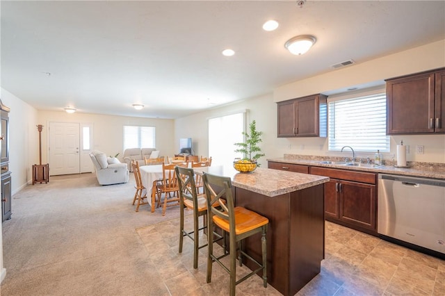 kitchen with visible vents, a sink, stainless steel dishwasher, a kitchen breakfast bar, and a center island