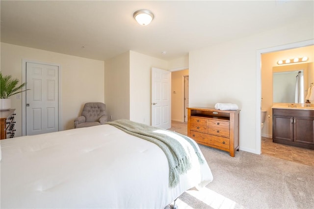 bedroom with connected bathroom, light carpet, and baseboards