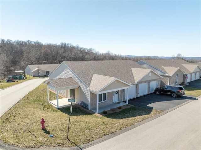 view of front of property featuring a front yard, driveway, an attached garage, a shingled roof, and a residential view