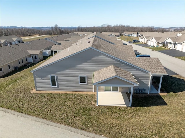 view of property exterior with a lawn, a residential view, and roof with shingles