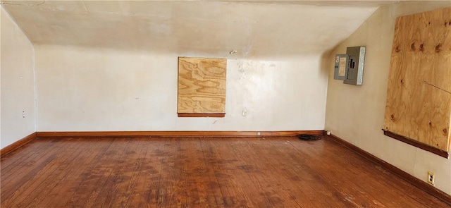 empty room featuring hardwood / wood-style flooring, electric panel, and baseboards