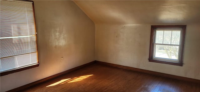 additional living space with baseboards, dark wood-type flooring, and vaulted ceiling