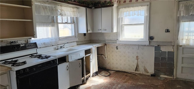 kitchen featuring light countertops, white cabinets, gas stove, and a healthy amount of sunlight