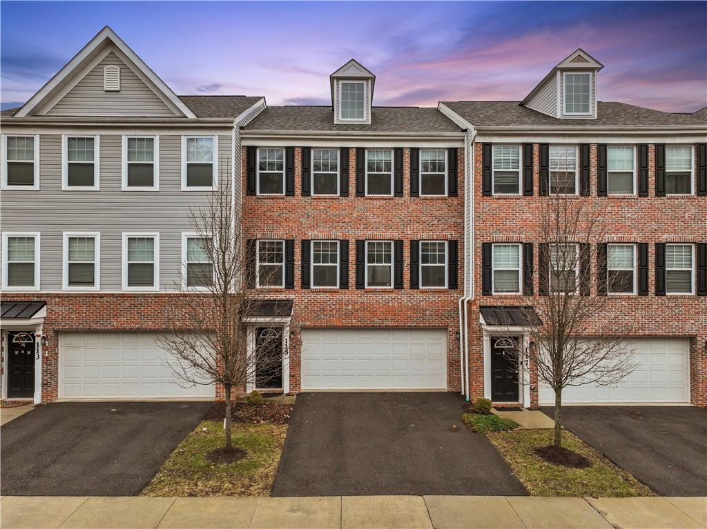view of property featuring a garage, brick siding, and driveway