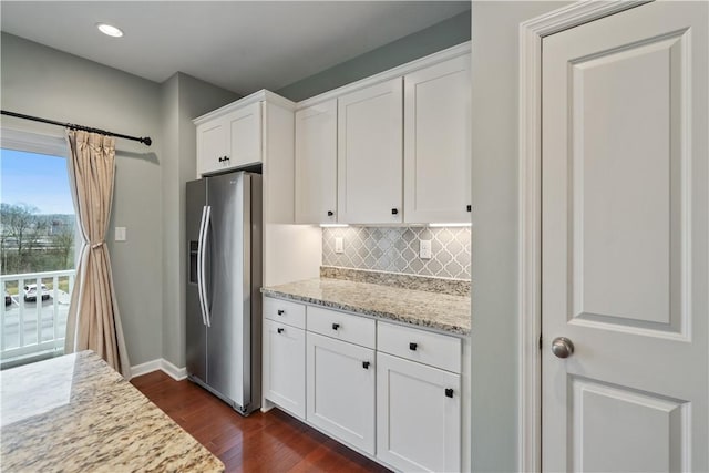 kitchen featuring tasteful backsplash, dark wood finished floors, light stone counters, white cabinets, and stainless steel fridge