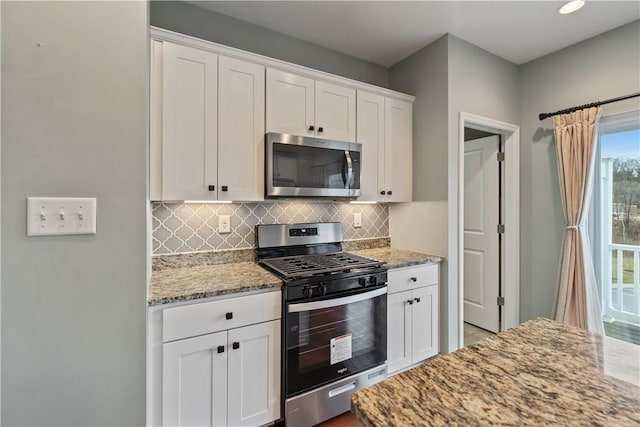 kitchen featuring decorative backsplash, white cabinetry, stainless steel appliances, and light stone countertops