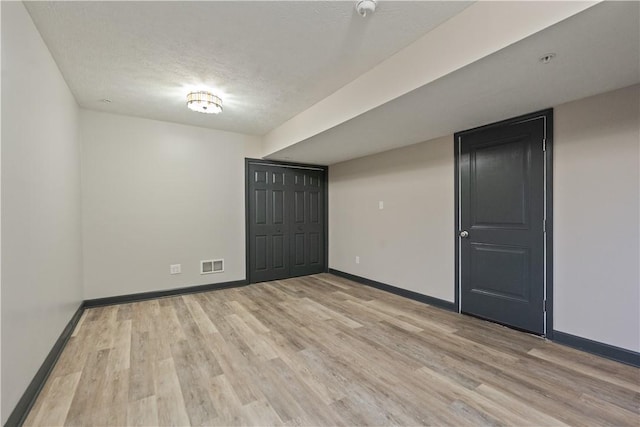 spare room featuring visible vents, baseboards, and light wood finished floors