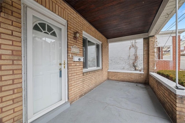 doorway to property featuring brick siding and covered porch