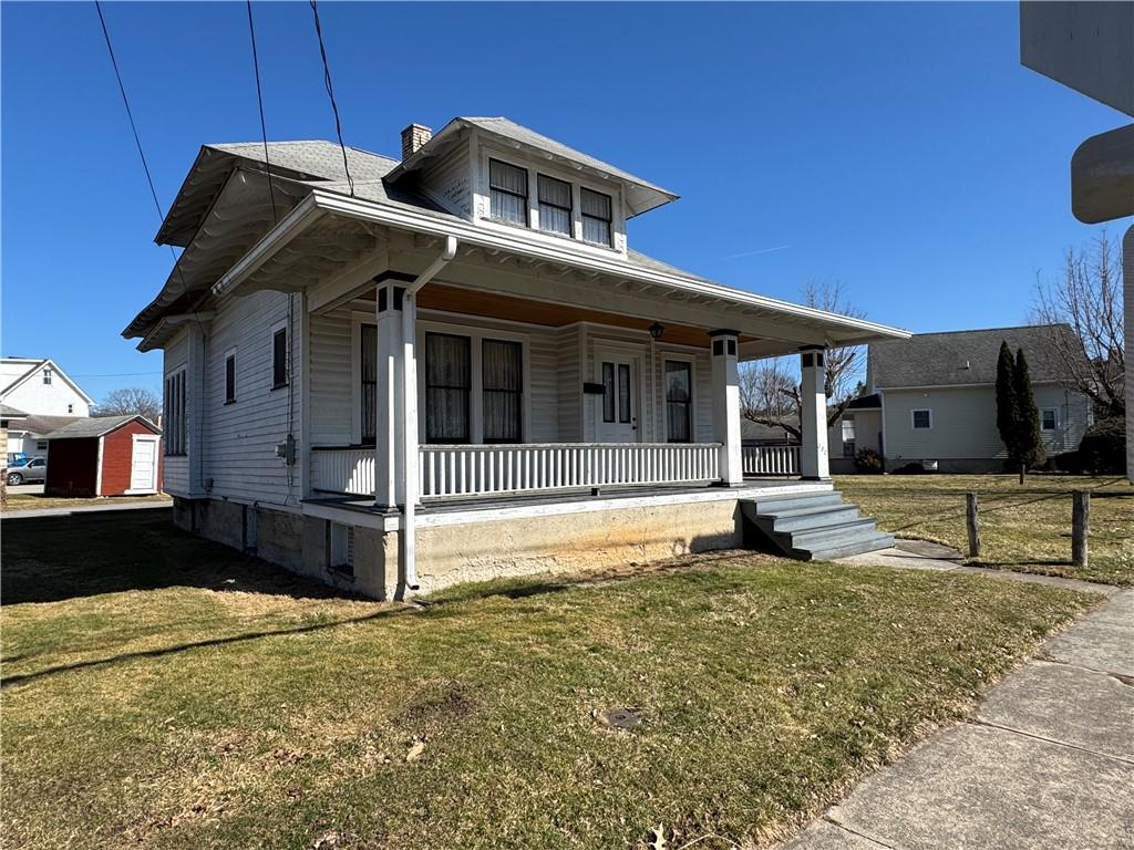 view of front of house with a front yard, covered porch, and a chimney