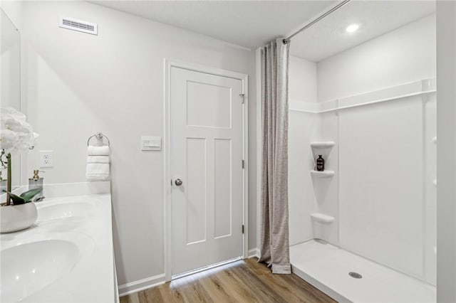 175 Shelton Place Dr, Connoquenessing Boro, PA 16033 - bathroom featuring visible vents, double vanity, wood finished floors, a shower stall, and a sink