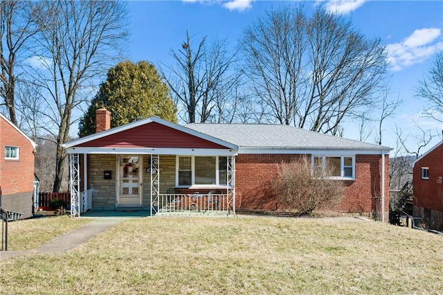 view of front of home with a porch, brick siding, a front lawn, and a chimney