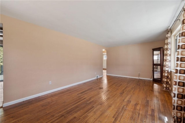 spare room featuring baseboards and hardwood / wood-style flooring