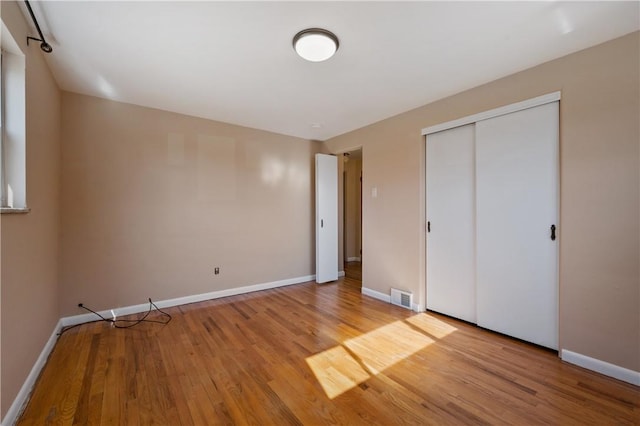 unfurnished bedroom featuring a closet, visible vents, light wood-type flooring, and baseboards