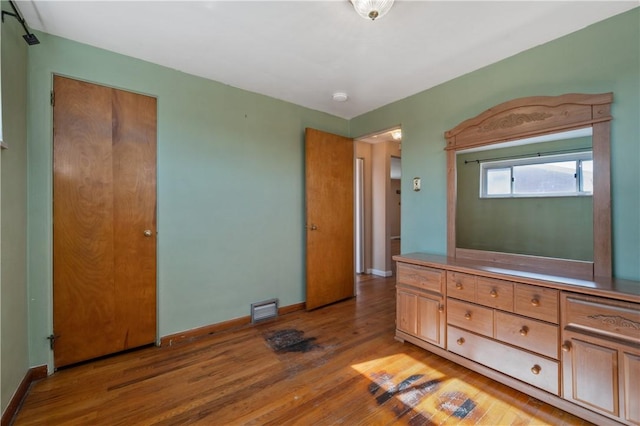 unfurnished bedroom with a closet, visible vents, baseboards, and light wood-style floors