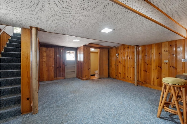 below grade area featuring stairway, carpet flooring, and wood walls