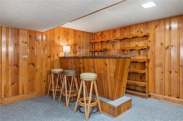 bar featuring a bar, wood walls, and carpet floors