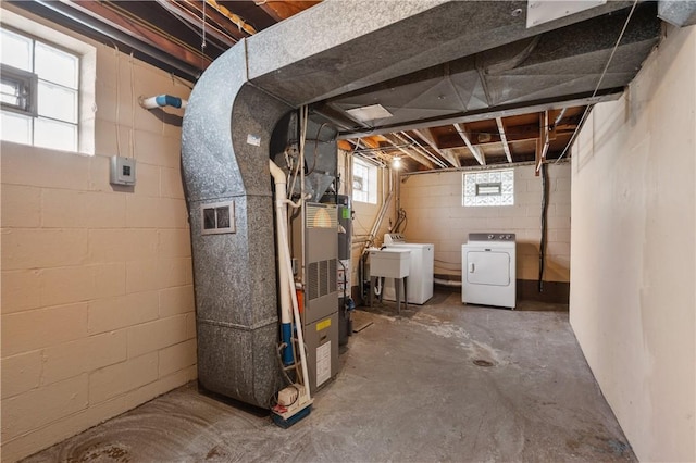 below grade area with washer and dryer, heating unit, and a sink