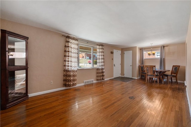 interior space featuring a notable chandelier, visible vents, baseboards, and hardwood / wood-style floors