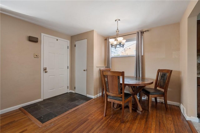 dining space featuring dark wood-style floors, a notable chandelier, visible vents, and baseboards