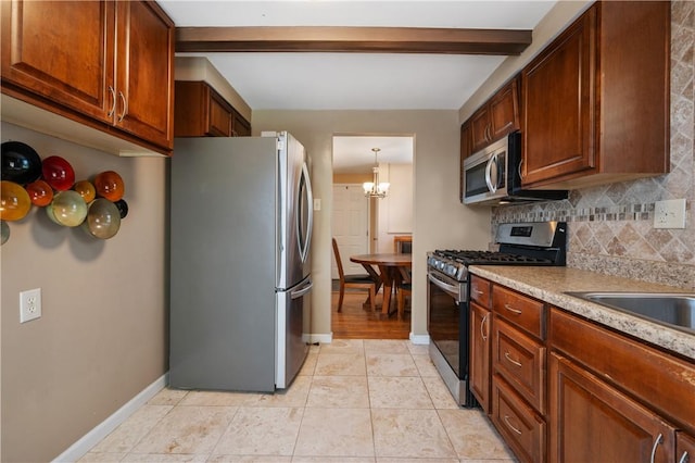 kitchen with light tile patterned floors, baseboards, decorative backsplash, light countertops, and appliances with stainless steel finishes